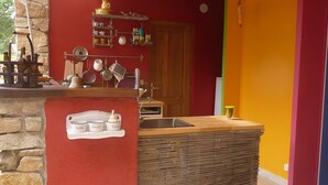 A kitchen area with a stone wall, wooden counter, and various kitchen utensils. - Beautiful, quiet property with swimming pool, spa and stone outbuilding + air conditioning (Privas)