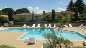 A pool area with multiple lounge chairs and a clear blue pool.
