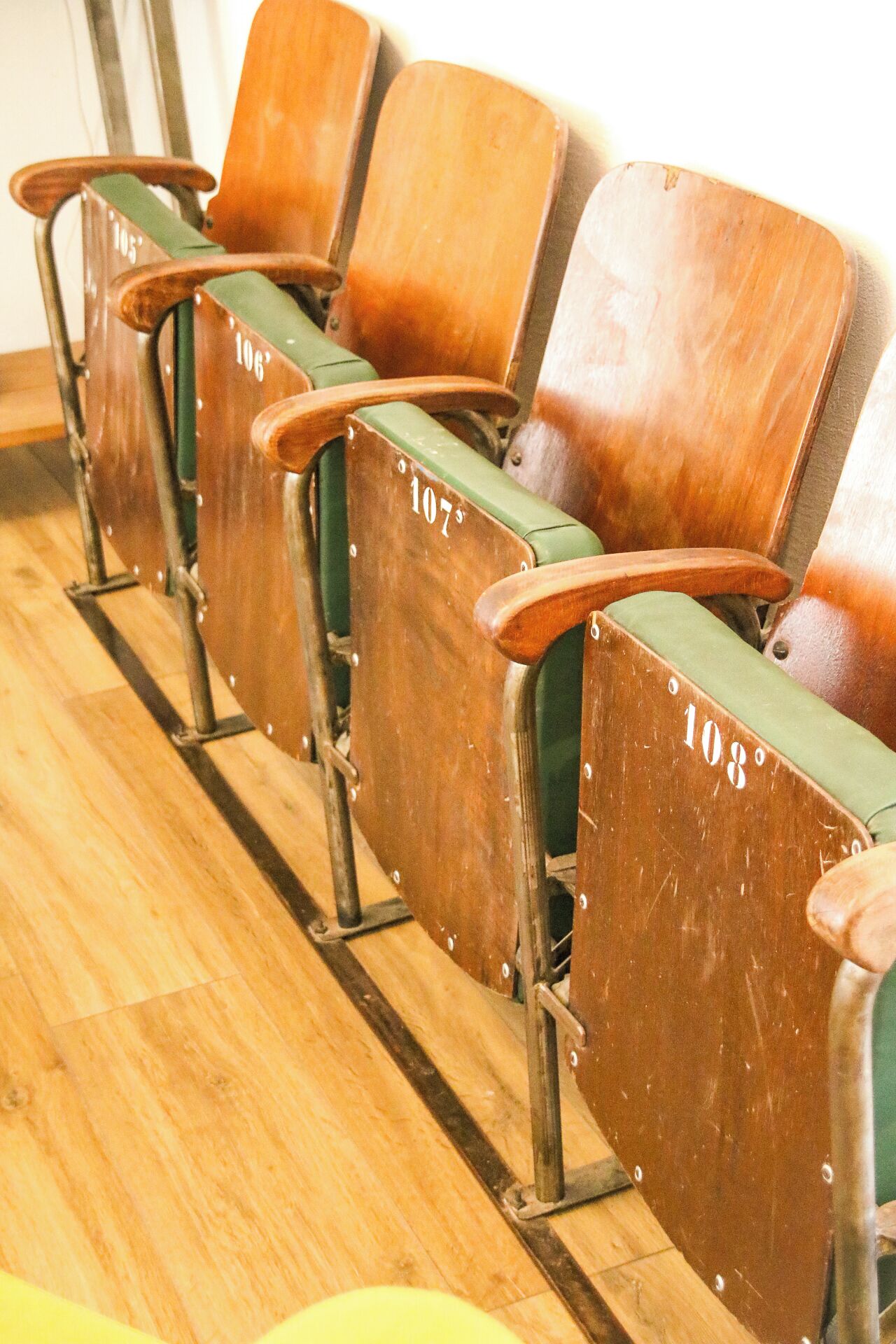 A row of wooden chairs with metal frames, each labeled with a number.