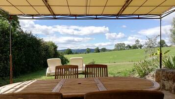 Relax in a serene outdoor seating area with a table and chairs, surrounded by lush greenery and a picturesque view.