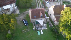 Un pueblo rural con casas de piedra, un camino pavimentado y un coche estacionado frente a una vivienda.