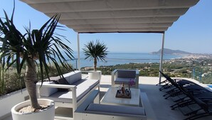 A rooftop terrace with outdoor seating, a potted palm tree, and a view of the sea. - Luxury villa near the sea with wonderful sea view, infinity swimming pool, south (Altea)