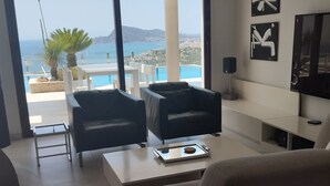 A modern living room with a sofa, two armchairs, a coffee table, and a TV. There is a balcony with a view of the sea and mountains. - Luxury villa near the sea with wonderful sea view, infinity swimming pool, south (Altea)