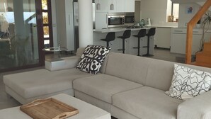 A modern living room with a sectional sofa, a wooden side table, and a glass door leading to another room. - Luxury villa near the sea with wonderful sea view, infinity swimming pool, south (Altea)