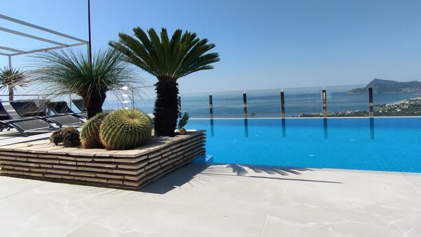 A pool area with lounge chairs and palm trees, overlooking a clear blue sky and distant land. - Luxury villa near the sea with wonderful sea view, infinity swimming pool, south (Altea)
