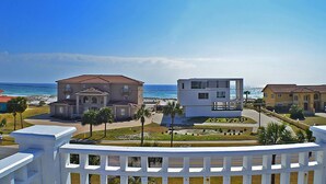 Uma área residencial costeira com casas modernas e tradicionais, céu azul límpido e vista para o oceano.