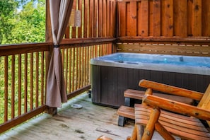A wooden deck with a hot tub, wooden benches, and a curtain.