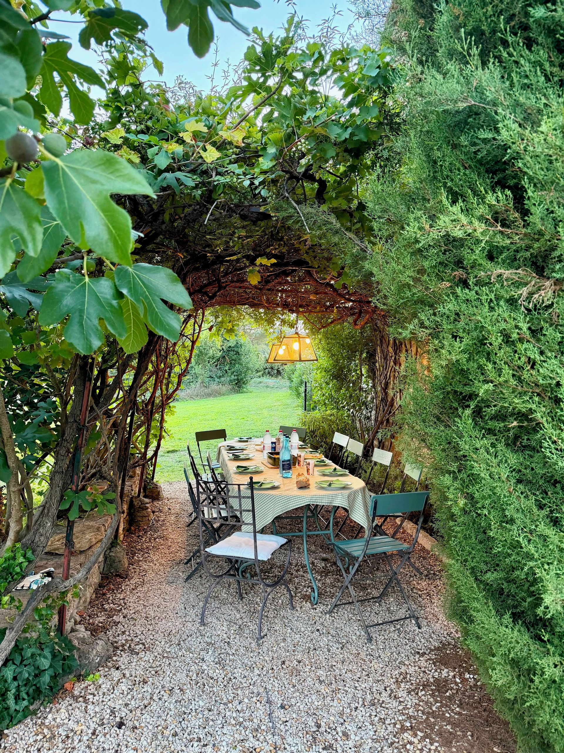 Ein Essbereich im Freien mit einem Tisch für vier Personen, umgeben von viel Grün und einem Pergola.