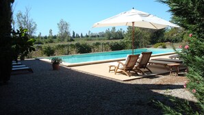 A poolside area with a pool, two lounge chairs, and a large umbrella. - On 2 hectares, air-conditioned Provencal farmhouse in idyllic Provence   (L'isle-Sur-La-Sorgue)
