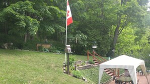 A flagpole with a flag, a covered outdoor seating area, and a staircase leading up to a deck.
