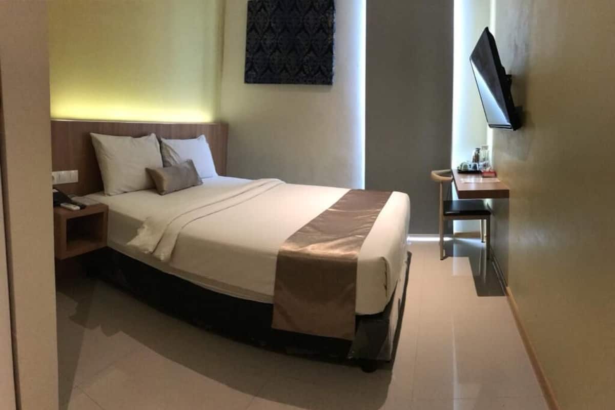 A neatly arranged hotel room with a bed, bedside table, and a flat-screen TV mounted on the wall.