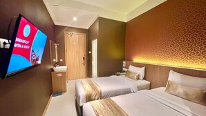 A hotel room with two beds, a TV mounted on the wall, a bathroom, and a patterned wall. - Deli Hotel (Medan)
