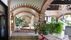 A spacious interior with a central courtyard, stone arches, and a variety of plants.