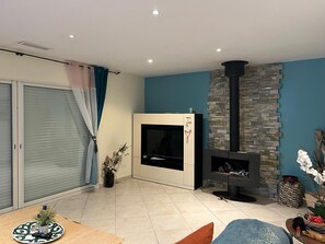 A modern living room with a fireplace, a sliding glass door, and a blue accent wall.