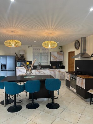 A modern kitchen with a central island, bar stools, pendant lighting, and a built-in oven. - Villa with exceptional view 2 minutes walk from Farinole beach (Farinole)