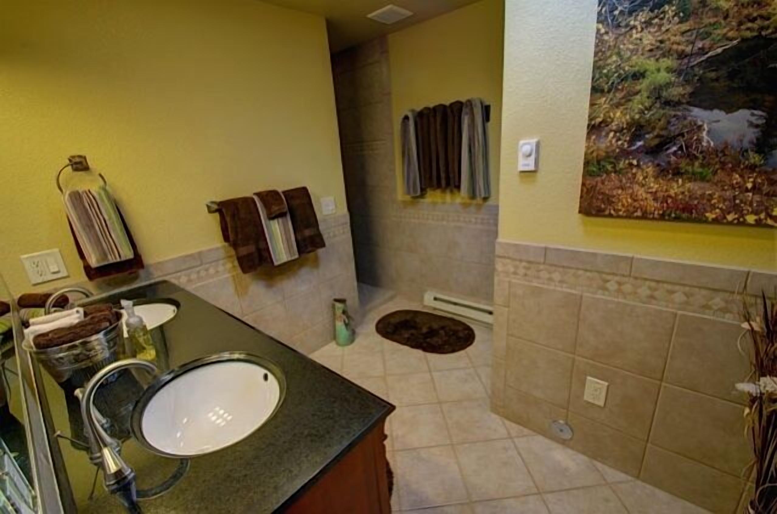 A bathroom with a sink, towel rack, and a painting on the wall.