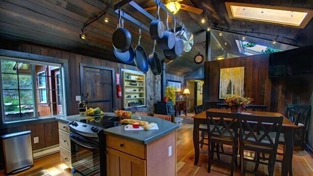 A kitchen with wooden cabinets, a central island, and hanging pots.