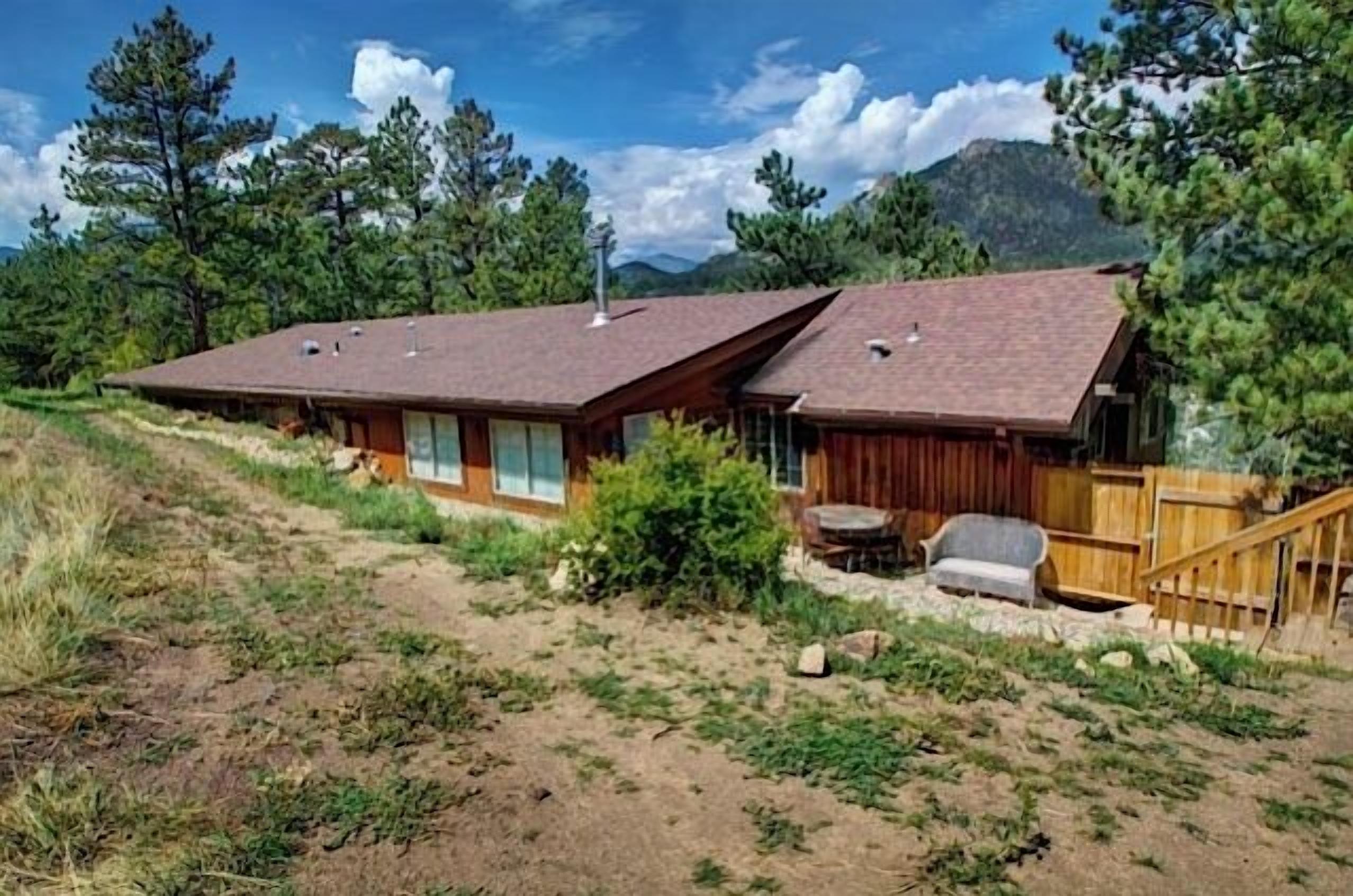 Une cabane avec un toit en pente, un revêtement extérieur en bois et une petite terrasse avec une chaise.