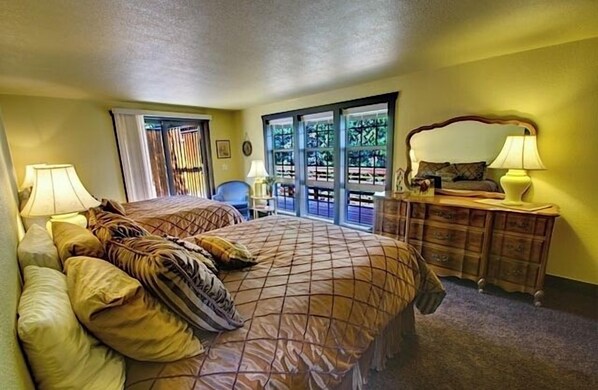 Un dormitorio con una cama grande, un aparador y una silla. Se ve una ventana con vistas a árboles.