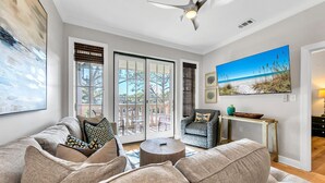 A living room with a sofa, armchairs, a coffee table, and a painting of a beach scene.