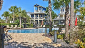 A pool area with lounge chairs, a clear sky, and a two-story building with balconies.