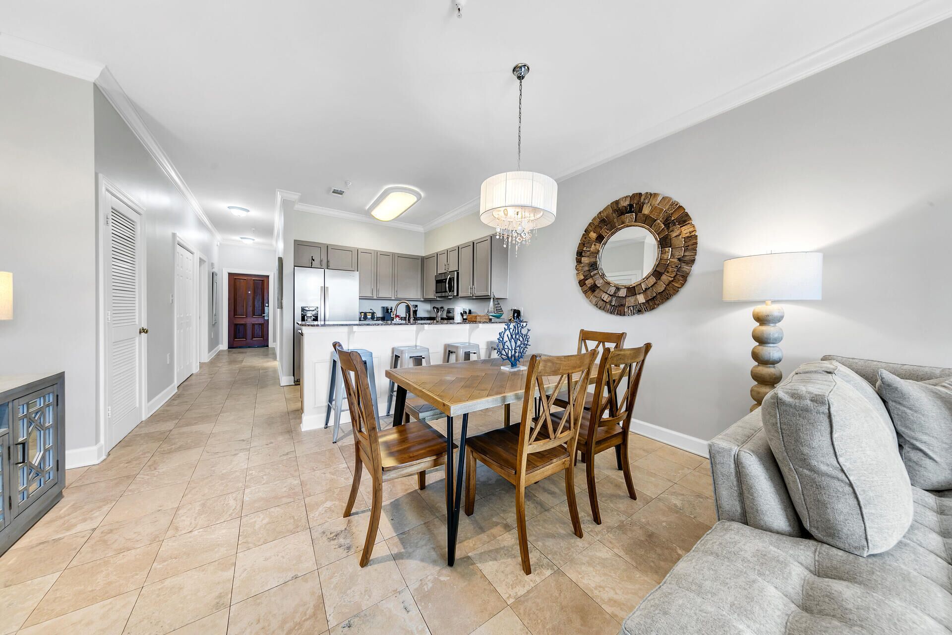 A modern kitchen with a central island, a dining area with wooden chairs, and a grey sofa.