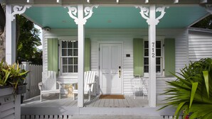A porch with white railings, a door, and two windows with shutters. - Historic Old Town  Key West Cigarmaker's Cottage - Cigar House, Sleeps 4 (Key West)