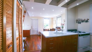 A kitchen with wooden cabinets, a white countertop, and a gas stove. - Historic Old Town  Key West Cigarmaker's Cottage - Cigar House, Sleeps 4 (Key West)