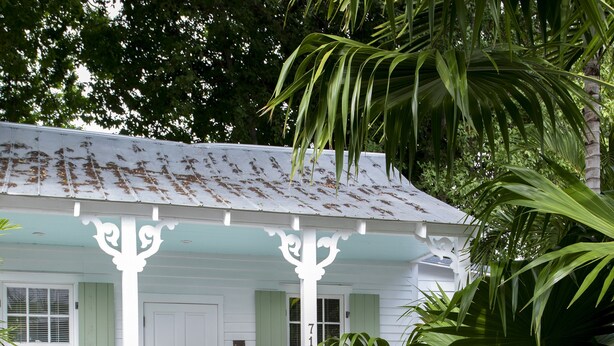 A white building with a porch, a pool, and tropical plants. - Historic Old Town  Key West Cigarmaker's Cottage - Cigar House, Sleeps 4 (Key West)