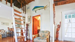 A spacious living room with a wooden staircase, a large fish decoration, and a tropical chair. - Historic Old Town  Key West Cigarmaker's Cottage - Cigar House, Sleeps 4 (Key West)