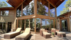 Un terrazzo in legno con mobili in vimini e pareti di vetro.