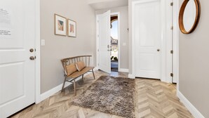 Un couloir avec un banc, un tapis et deux portes.