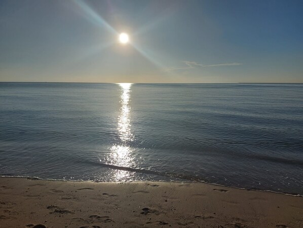 A beach with footprints in the sand and a calm sea reflecting the sun. - Beachfront Property, Ocean Views! (Hollywood)