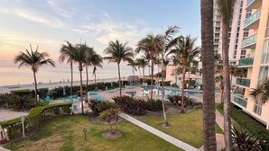 Een resort met een zwembad, palmbomen en uitzicht op de oceaan.