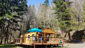 Una cabaña de madera con terraza, mobiliario exterior y una bandera estadounidense.