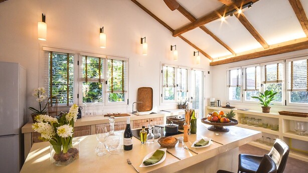 Una cocina con una isla central, vigas de madera y ventanas amplias.
