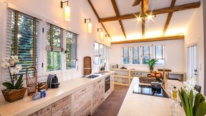 Una cocina moderna con una isla central, ventanas amplias y vigas de madera en el techo.