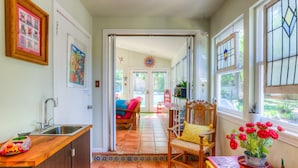 A kitchen with a sink, a wooden counter, and a dining area with a chair and table. - The CHA CHA CHA is a colorfully decorated home in a desirable neighborhood. (Austin)