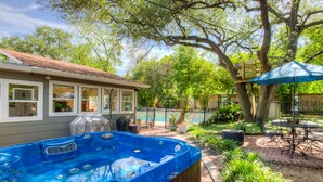 A backyard with a hot tub, patio furniture, and a wooden fence. - The CHA CHA CHA is a colorfully decorated home in a desirable neighborhood. (Austin)