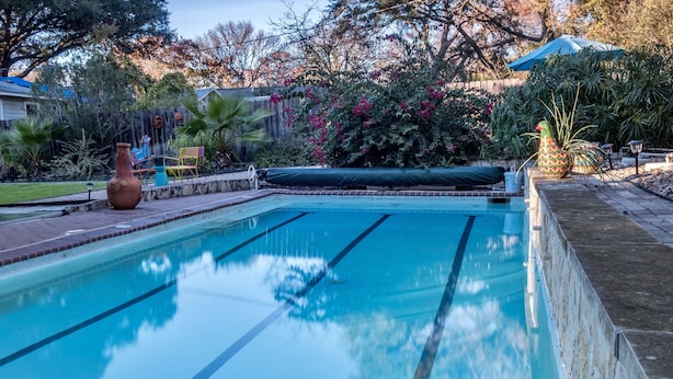 A rectangular swimming pool with clear blue water, surrounded by a brick deck. - The CHA CHA CHA is a colorfully decorated home in a desirable neighborhood. (Austin)