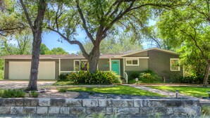 A two-story house with a garage, a front porch, and a well-maintained lawn. - The CHA CHA CHA is a colorfully decorated home in a desirable neighborhood. (Austin)