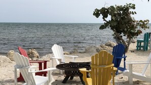 Un espace de détente aménagé sur la plage, avec des fauteuils Adirondack et un foyer.