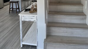 Une cuisine moderne avec des meubles blancs, un îlot central et un escalier avec des marches en bois et des rampes en métal.