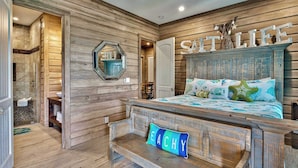 A bedroom with a wooden headboard, a bed with a blue and white floral bedspread, and a 'SITLIFE' sign on the wall.