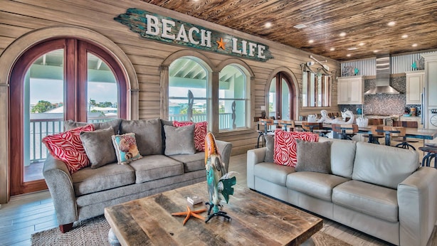 A beach-themed living room with two sofas, a coffee table, and a sign reading "BEACH LIFE".
