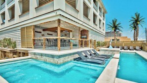 A hotel with a pool area, including lounge chairs and a bar.
