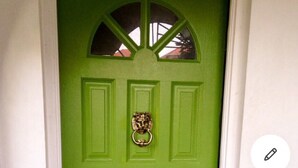 A green door with a brass knocker and a window above it. - GD Rooftop Lounge ocean view, salt water pool with mountain view, 1bdrm (West Gate Hills, Montego Bay)