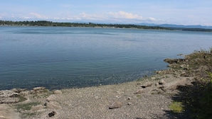 A calm lake with a rocky shoreline and distant mountains.