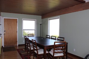 A dining room with a wooden table and chairs, large windows, and a wooden ceiling. - Family Home with Private Beach and Stunning Mountain Views (Lummi Island)