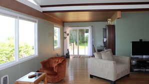 A spacious living room with a large window, a sofa, a chair, and a television.